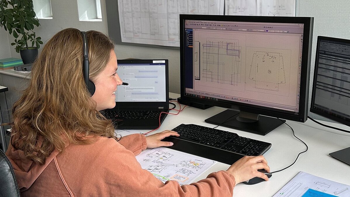 Eine junge Frau mit Headset arbeitet mit einem Grafikprogramm am Computer.