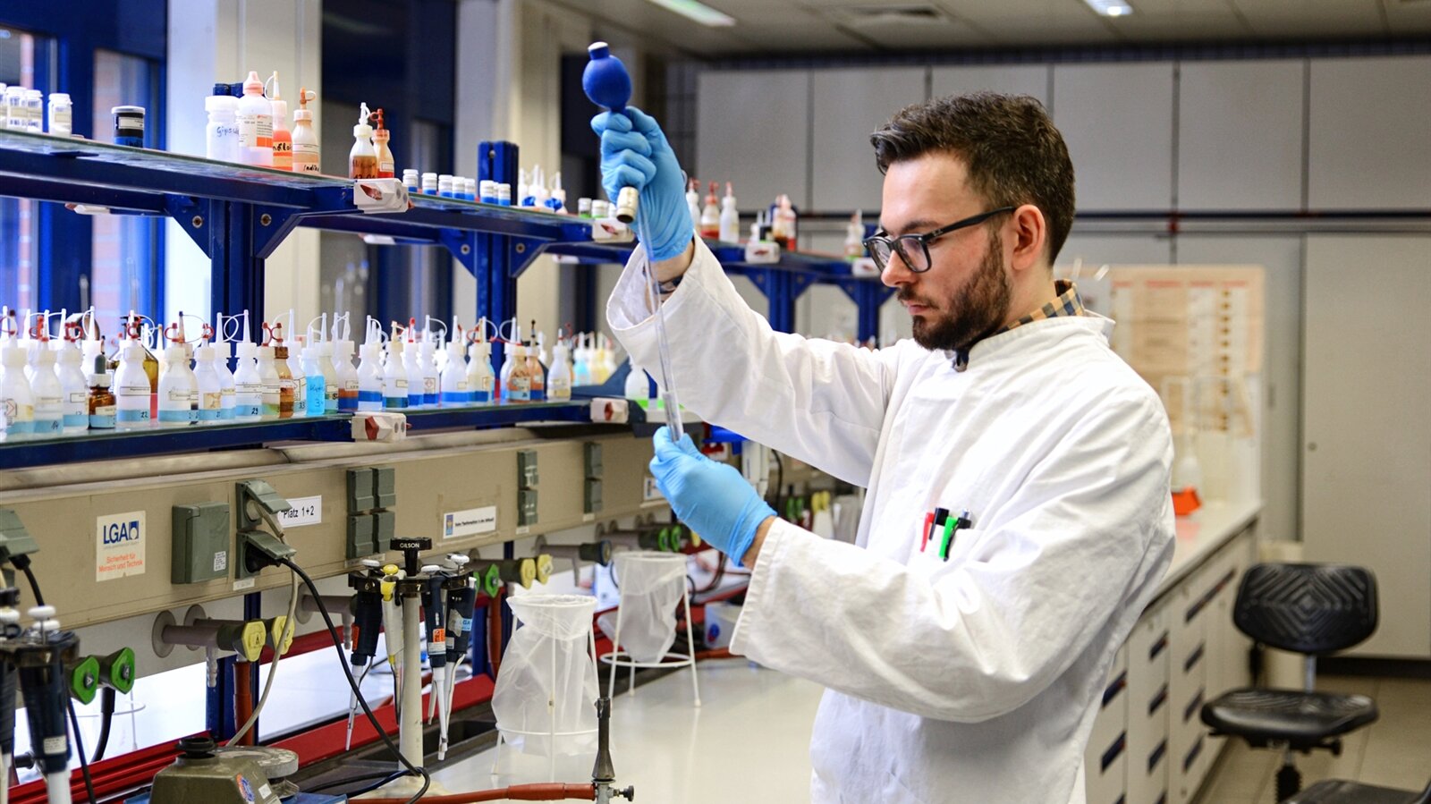 Ein Laborangestellter füllt mit einer Pipette eine Flüßigkeit in ein Reagenzglas.
