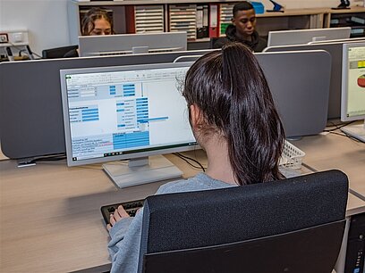 Eine junge Frau arbeitet an einem Computer.