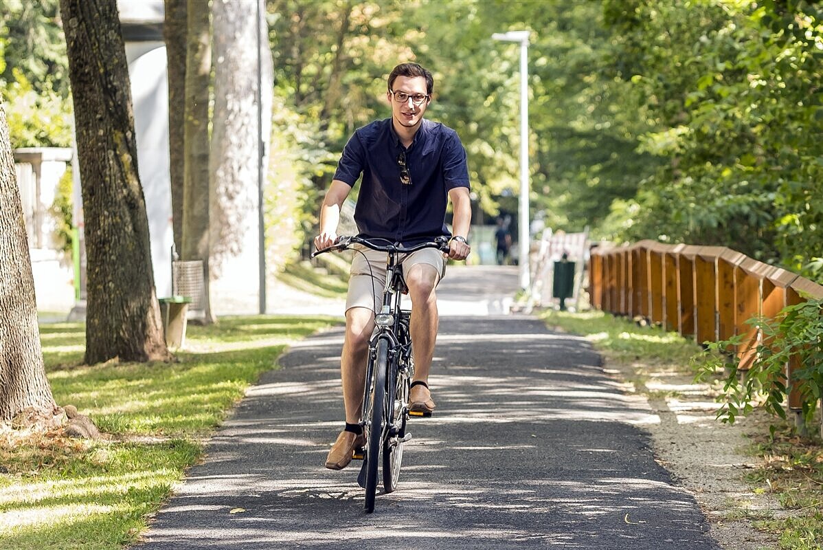 Ein Mann fährt mit einem Fahrrad durch einen Park.