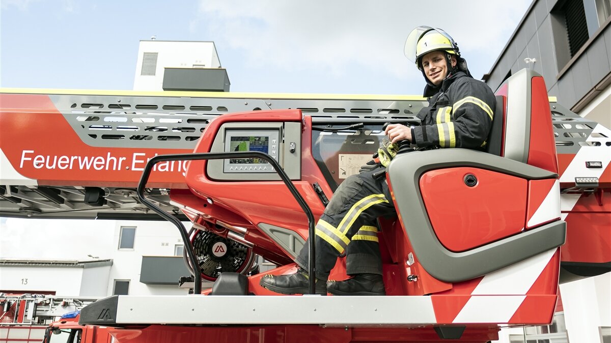 Ein junger Mann in Feuerwehr-Uniform sitzt auf dem Steuerungssitz des Feuerwehrkrans.
