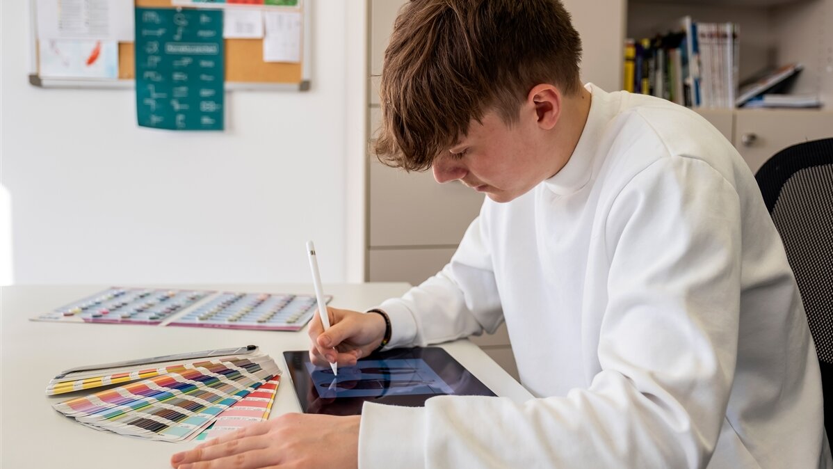Ein junger Mann zeichnet auf einem Tablet.