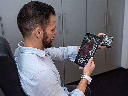 Ein Mann scannt einen Würfel mit einem Tablet.