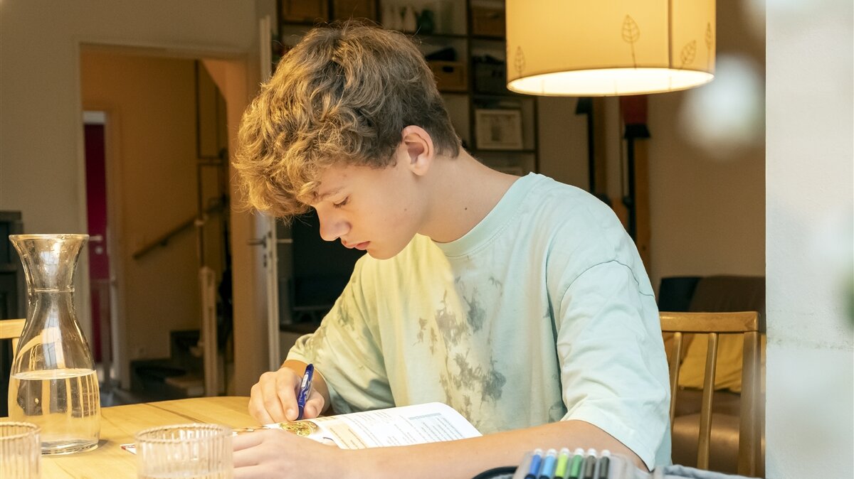 Ein Junge macht seine Hausaufgaben an einem Tisch.