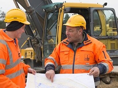 Zwei Baugeräteführer besprechen einen Bauplan.