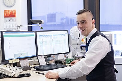 Ein junger Mann arbeitet an einem Computer mit zwei Bildschirmen.