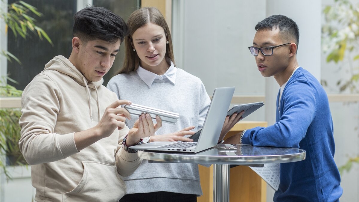 Eine Gruppe junger Menschen bespricht sich vor einem Computer.
