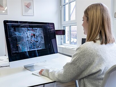 Eine junge Frau arbeitet in einem Büro am Computer.
